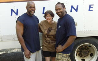 Two men and a woman standing in front of the truck