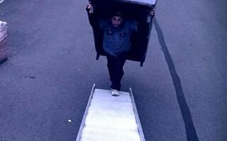 A man is carrying a big piece of furniture to the All Jersey Movers van